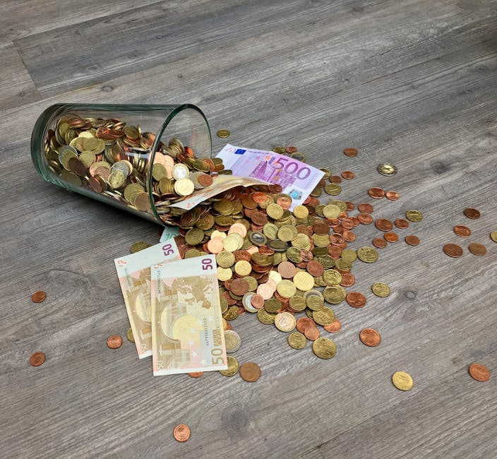 An overturned glass jar on a wooden floor spilling a mixture of euro banknotes and assorted coins, including 50 euro notes and various coins in copper and gold tones. The coins and notes are scattered across the surface, with some remaining inside the jar. The wooden floor features a natural grain pattern and appears clean and well-maintained. The scene highlights the importance of transparent and fair pricing practices in domestic and commercial cleaning services, as promoted by Kingston cleaners, to avoid hidden fees. Proper surface cleaning and equipment sanitation are implied to maintain hygiene and trust in professional cleaning services. The image has a neutral lighting setup, emphasizing the clarity of the money and the clean, textured surface of the floor.